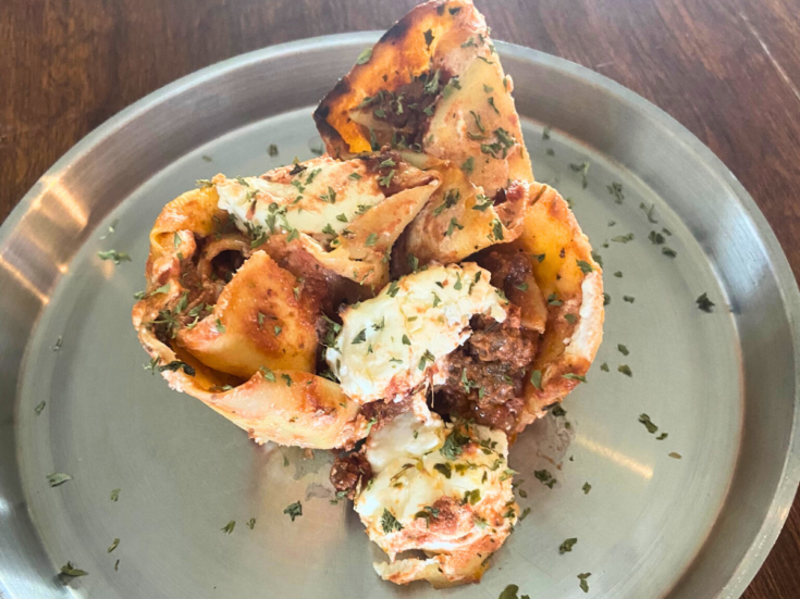 lasagna roses on a stainless steel plate on a wood dining table